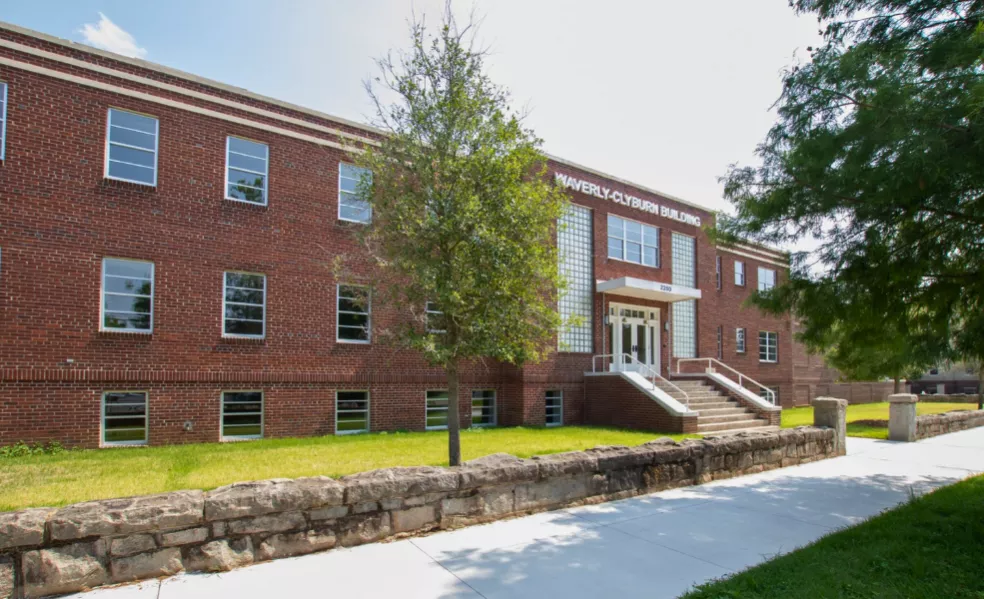 Red brick building with windows and stairs leading to the door.